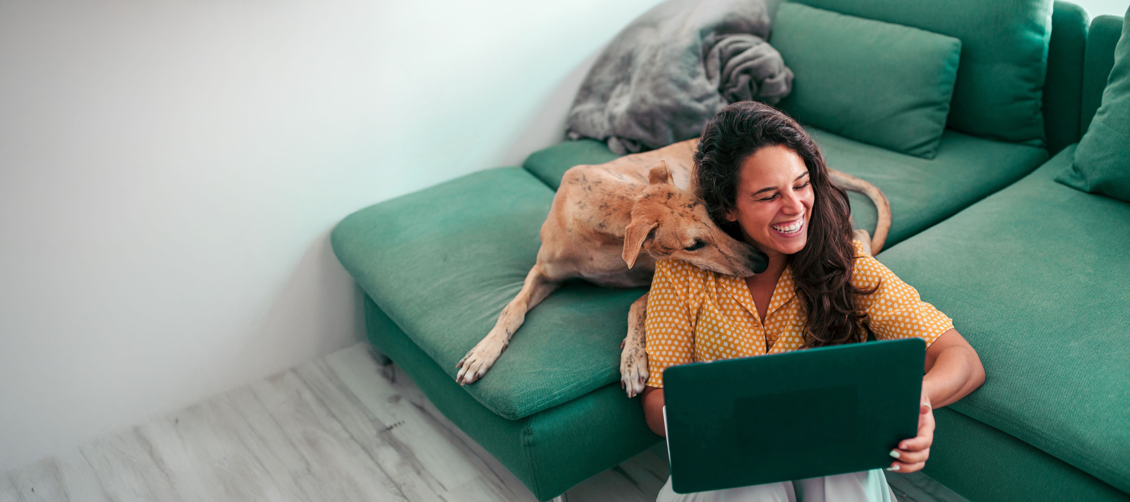 Woman with dog laughing plus green sofa